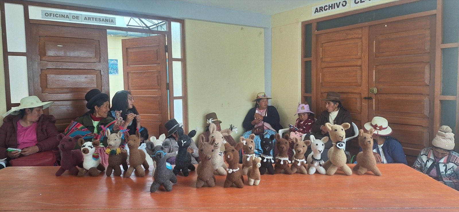 The finished alpaca and llama amigurumi displayed in front of the artisans who made them